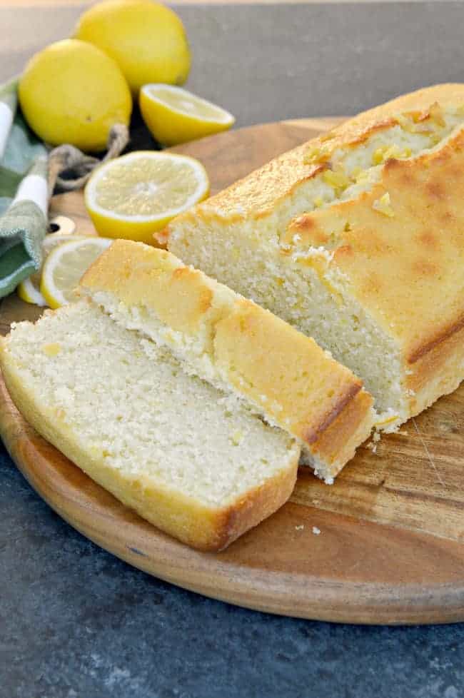 sliced lemon loaf on cutting board with lemons in background