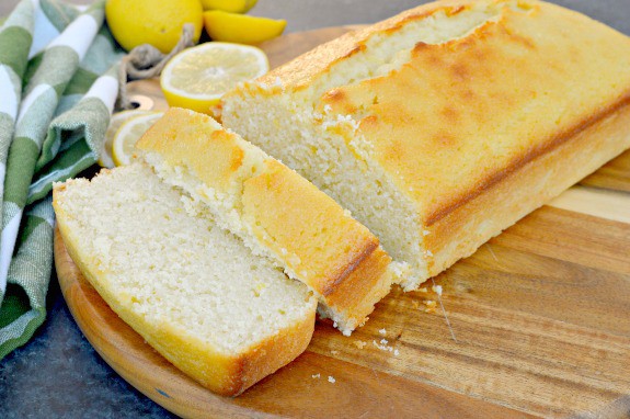 sliced lemon loaf on cutting board with lemons in background