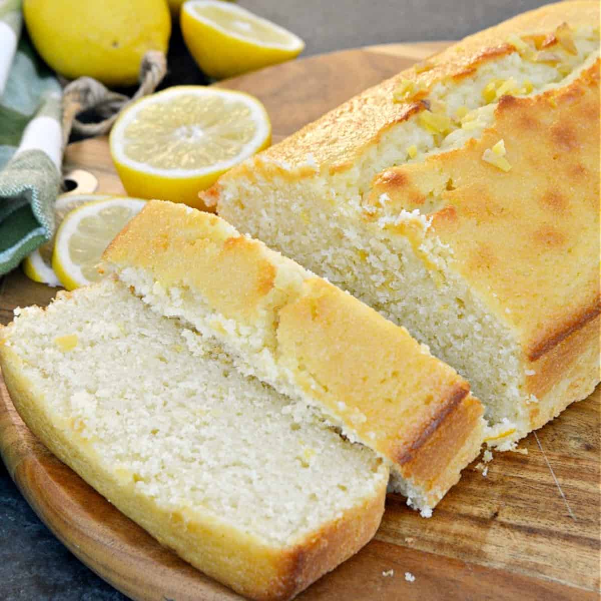 sliced lemon loaf on cutting board with lemons in background
