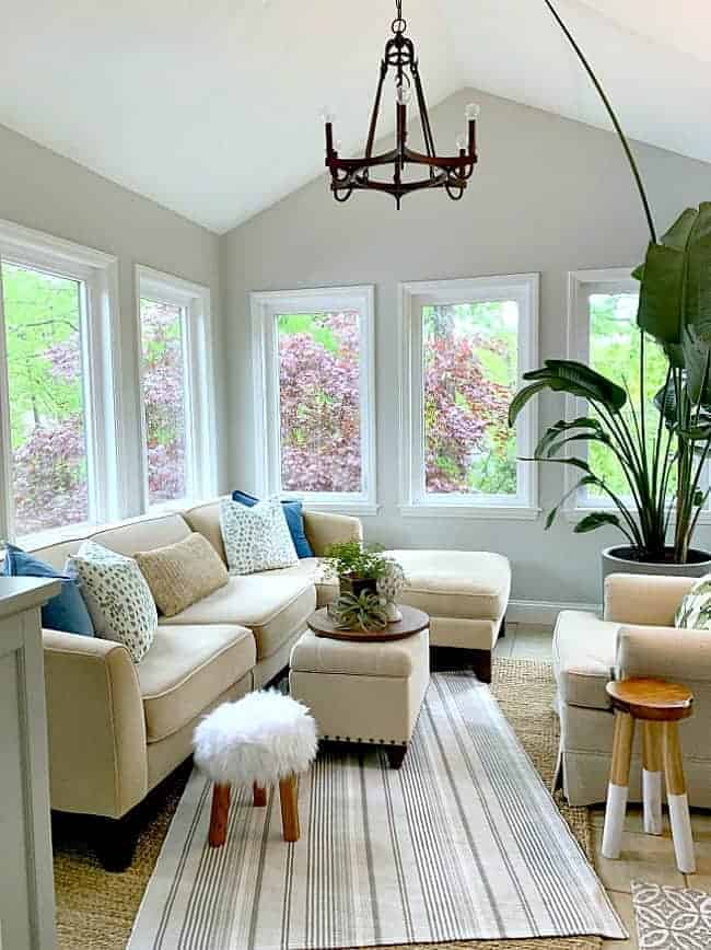 sunroom with sectional sofa, large hanging light and large plant in corner