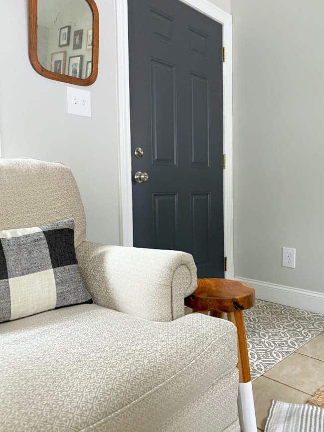 linen colored arm chair with dark gray painted door in the background