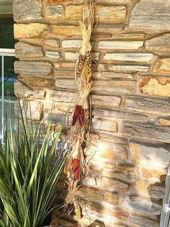 mini Indian corn and raffia hanger on stone wall