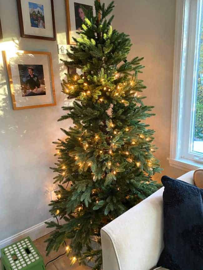 Christmas tree in corner of room with some lights not lit