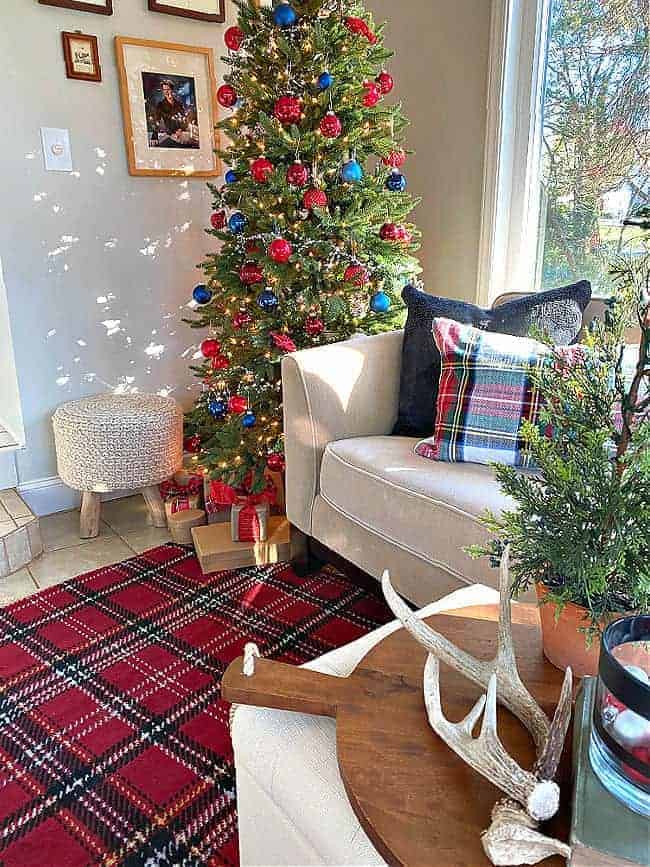 Christmas tree in corner of room with red and navy ornaments