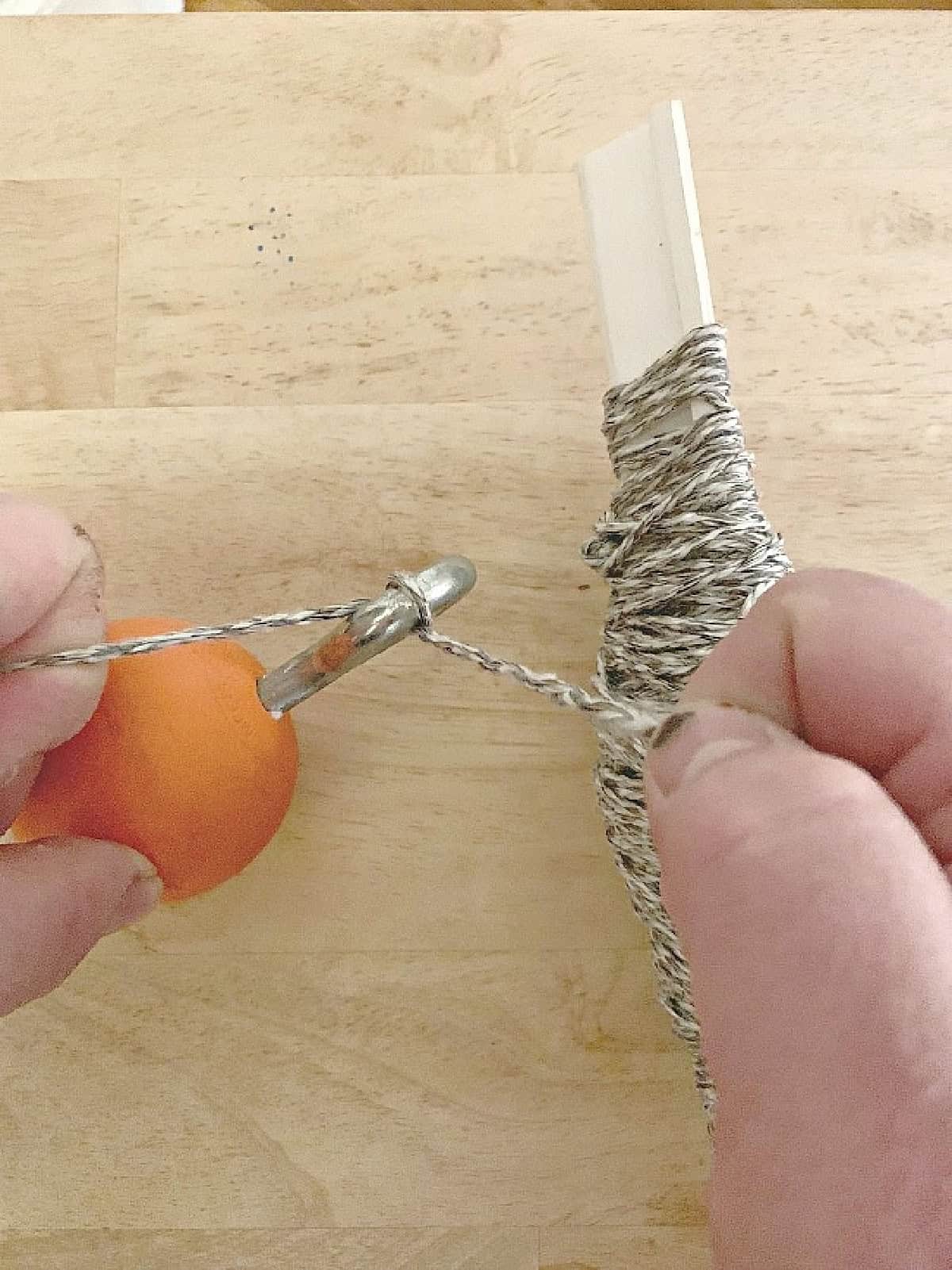 How to Make Lighted Christmas Balls (And How to Hang Them) weight and string string tied to orange lacrosse ball with an eye bolt in it