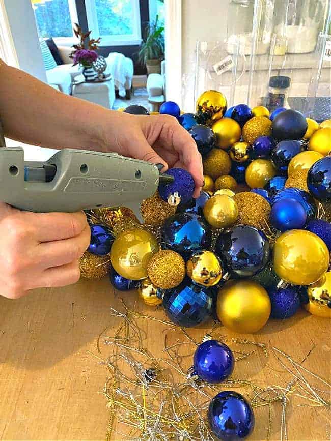 using hot glue gun to glue ornaments onto wreath