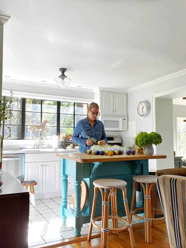 woman standing at kitchen island making ornament wreath