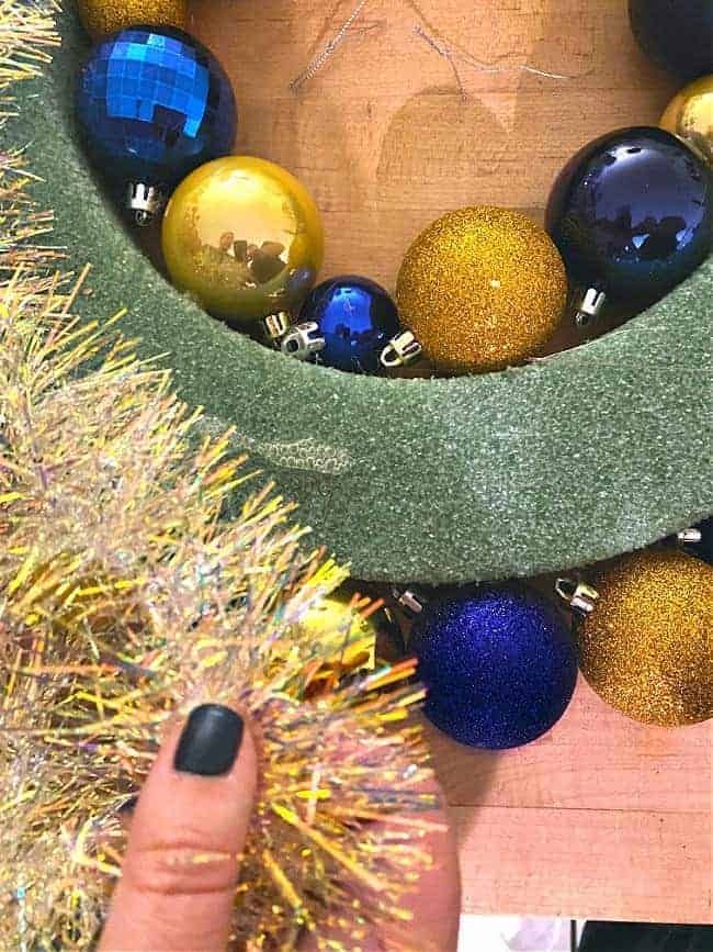 gluing tinsel to wreath form with hot glue