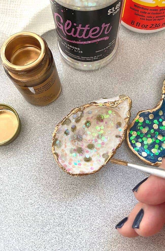 painting liquid gold leaf on the corners of a seashell ornament