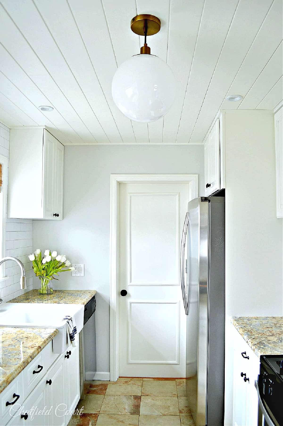 remodeled galley kitchen view of side of refrigerator and door to bedroom