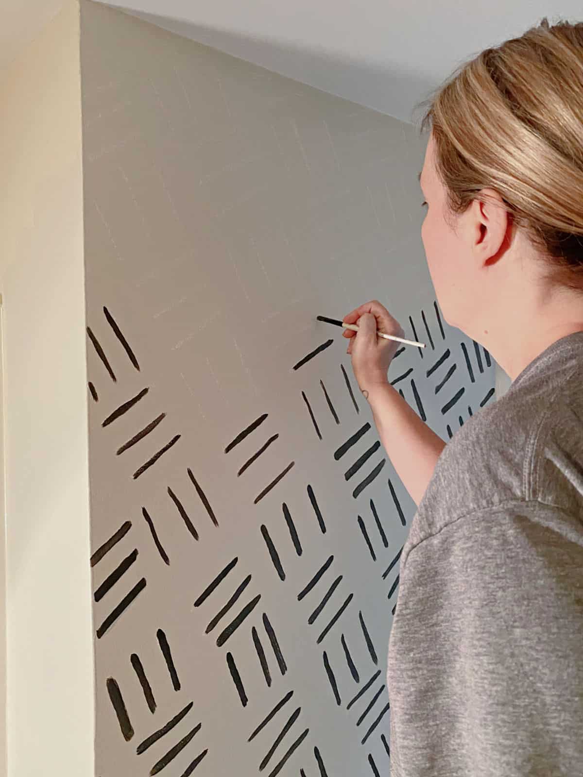 woman painting black lines on wall