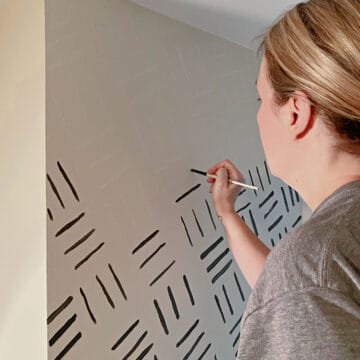 woman painting black lines on wall