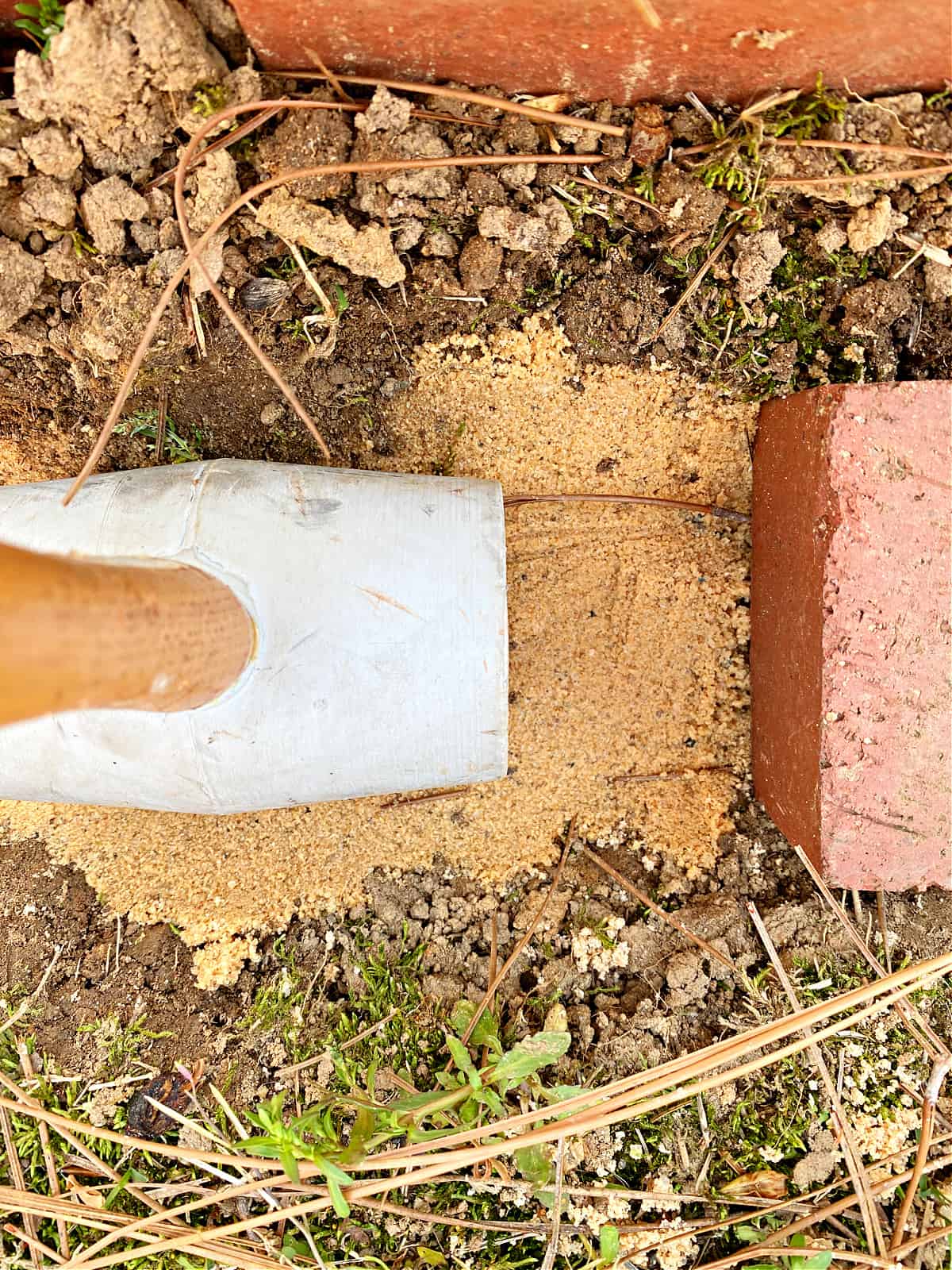 using a rubber mallet to tamp down sand for bricks