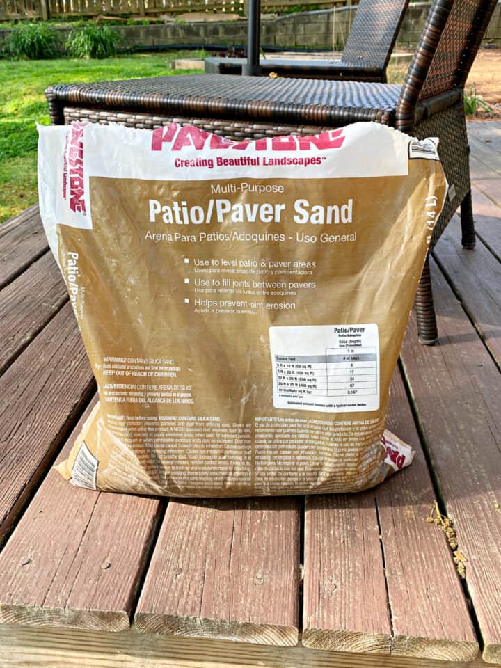 Laying Brick Edging In Your Garden picture bag of paver sand sitting on backyard deck