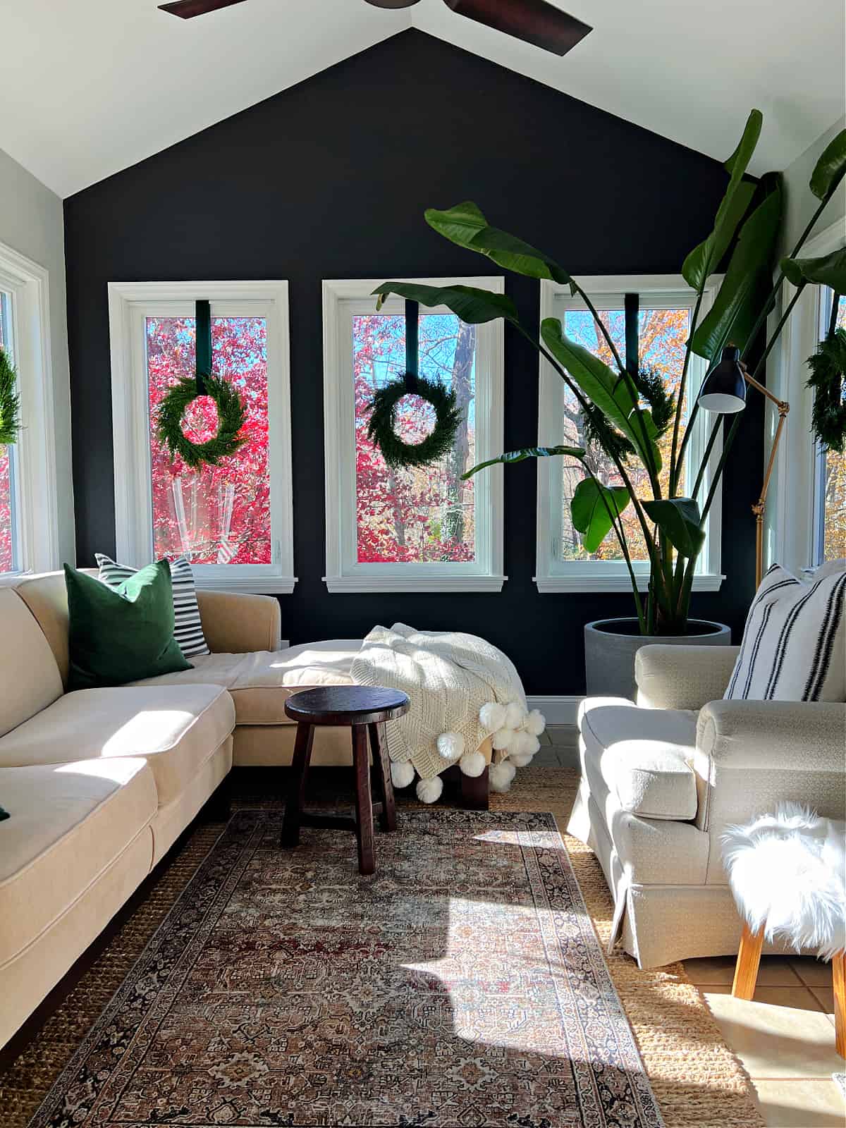 sunroom decorated for Christmas with wreaths hanging in windows