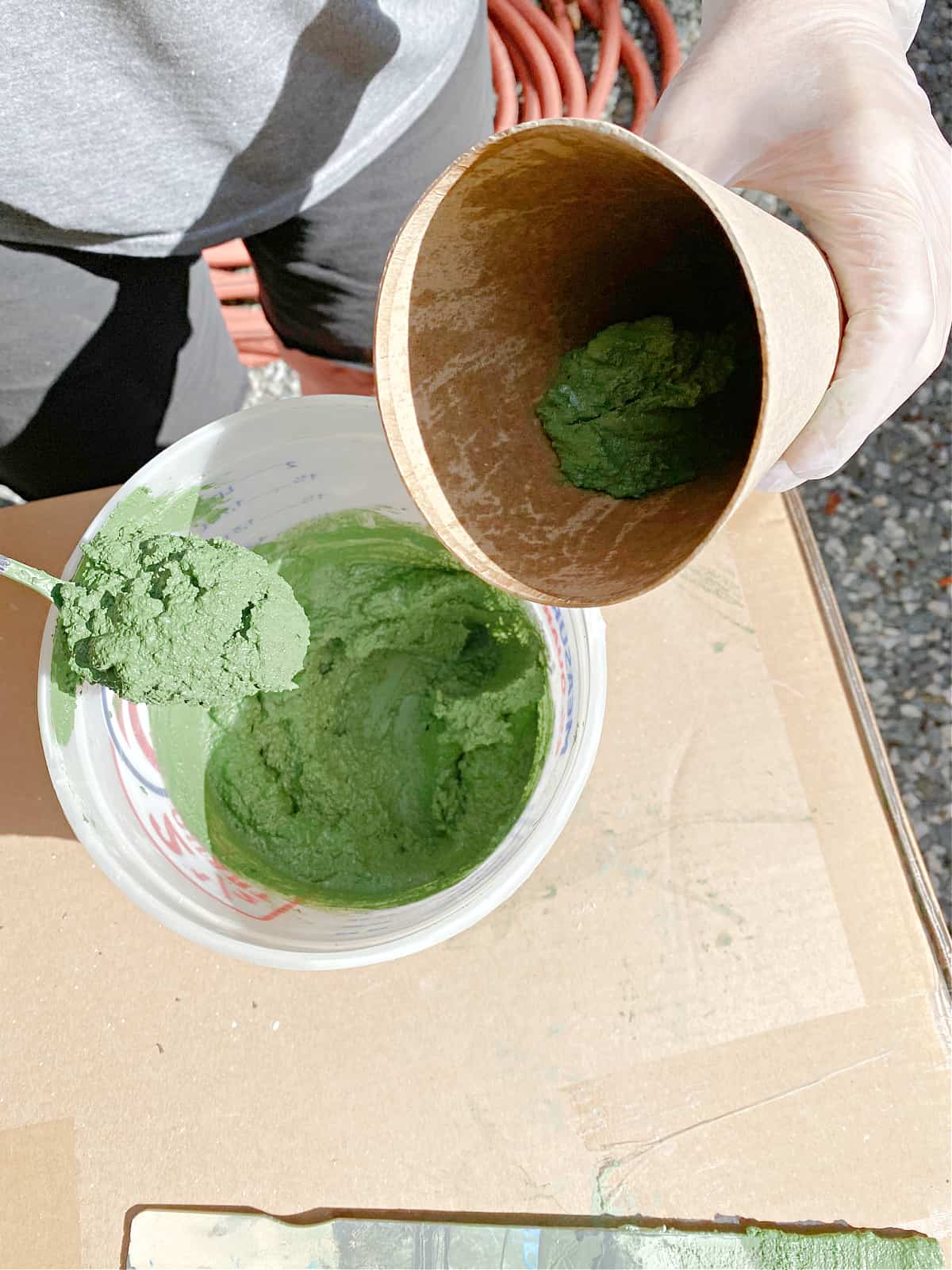 How to Make a Concrete Christmas Tree shot spooning green tinted concrete into cardboard cone