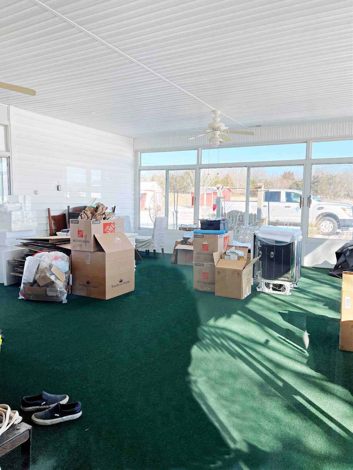 sunroom with green carpeting and boxes in it and 