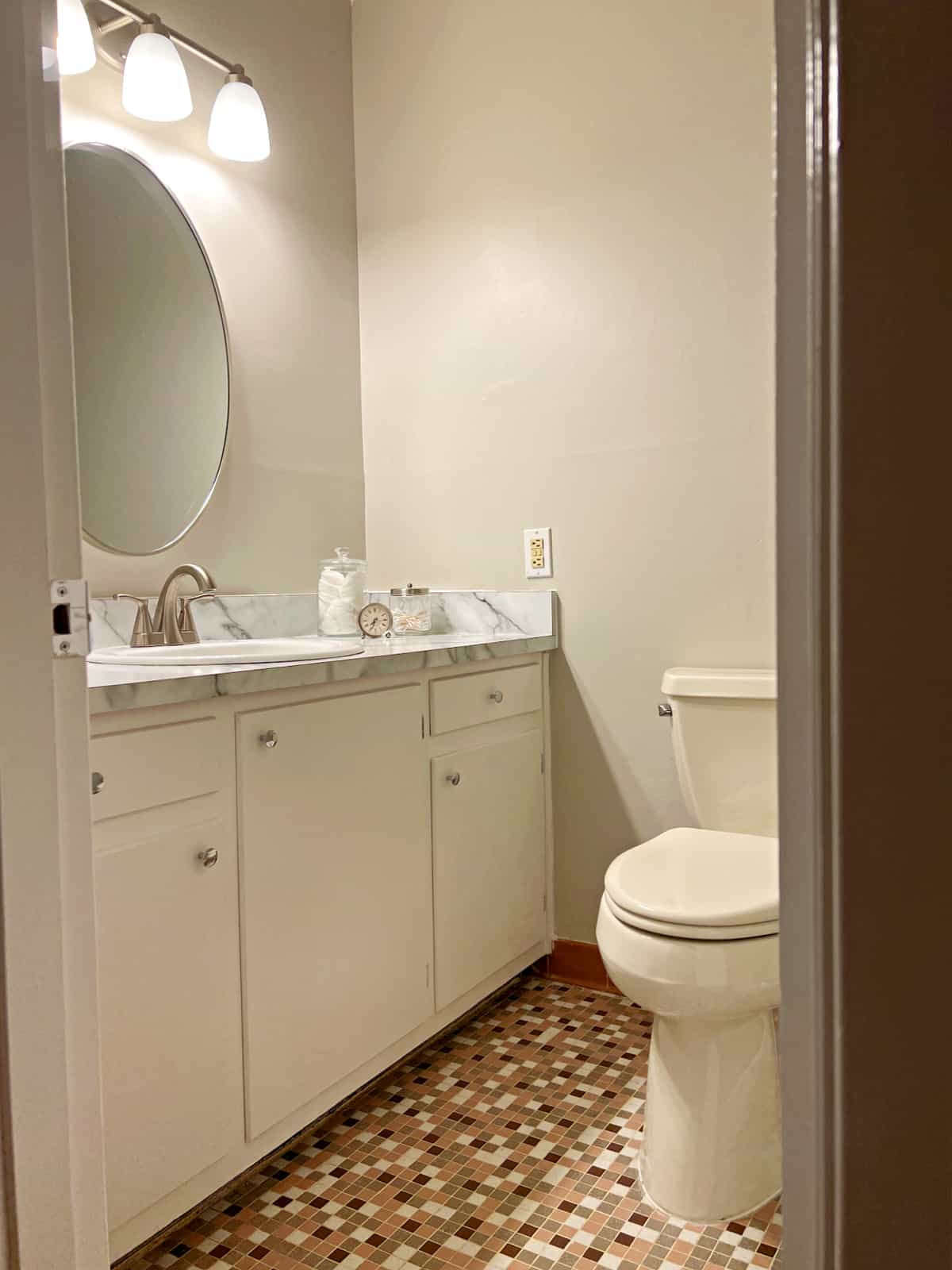 hallway bathroom with brown tile floor and white vanity