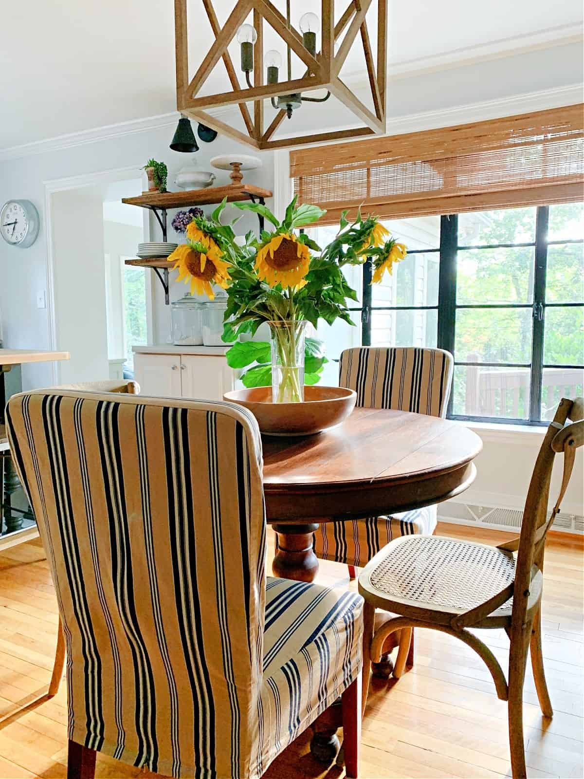 dining room table and chairs in room with large vase of sunflowers