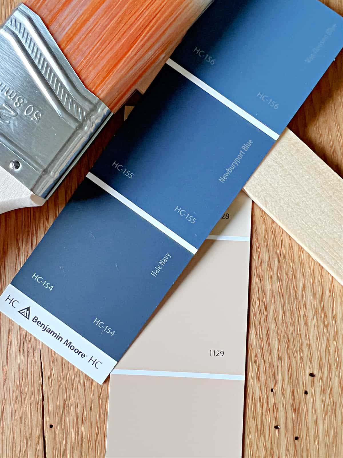 paint chips in navy blues and beige with paint brush and paint stick
