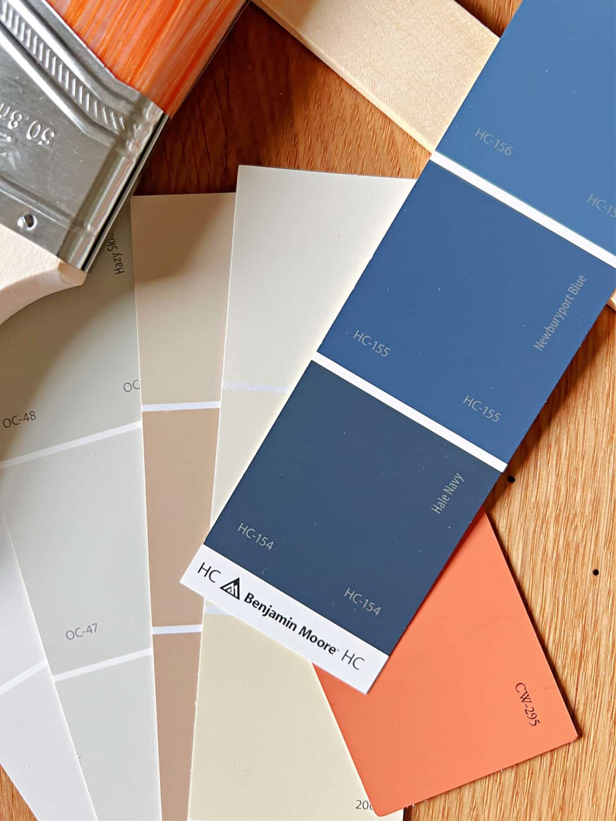 paint chips in navy blues, orange, beige and whites with paint brush and paint stick