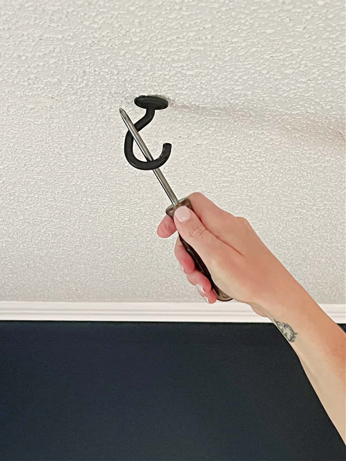 using a screwdriver to tighten ceiling light hook