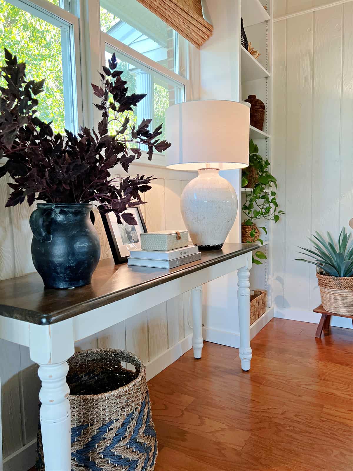 living room console table with vase with leaves and large lamp