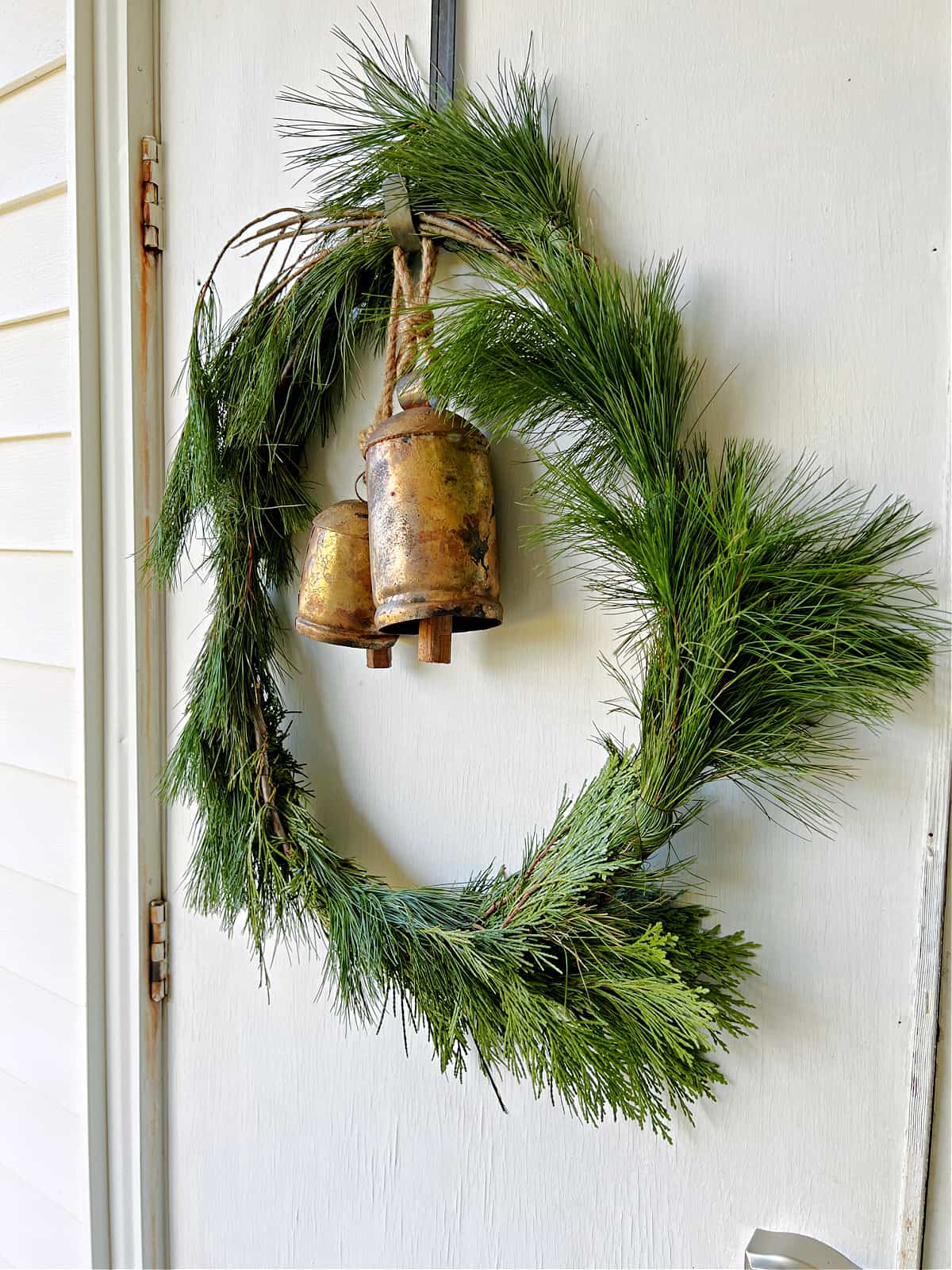 wreath with brass bells hanging on a white door