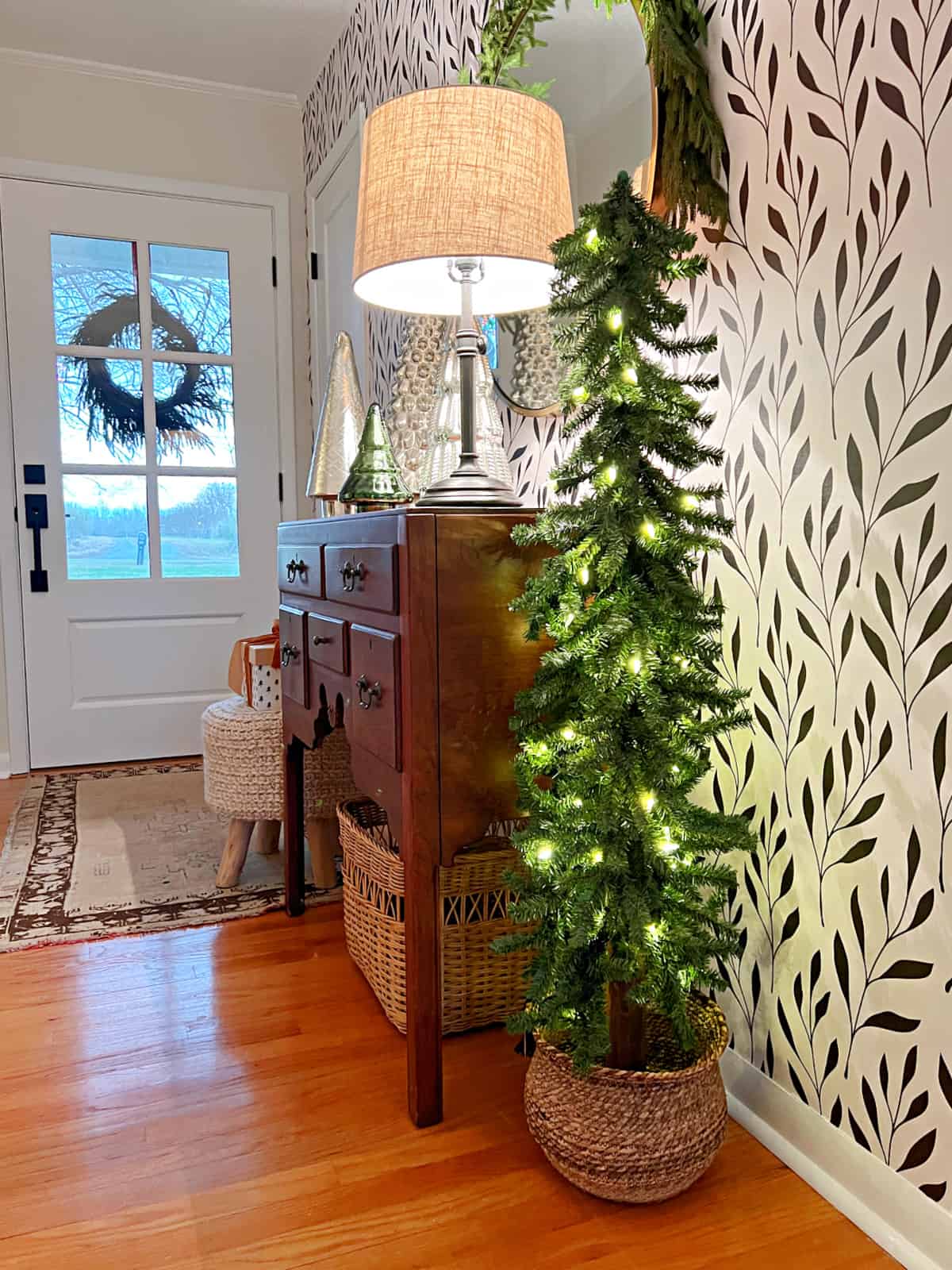 small entryway decorated for Christmas with a small skinny tree