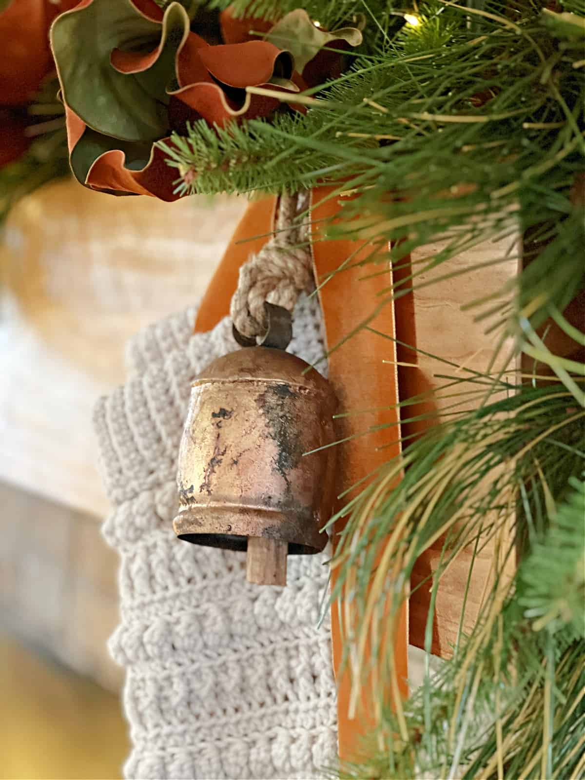 brass bell hanging on mantel decorated with garland
