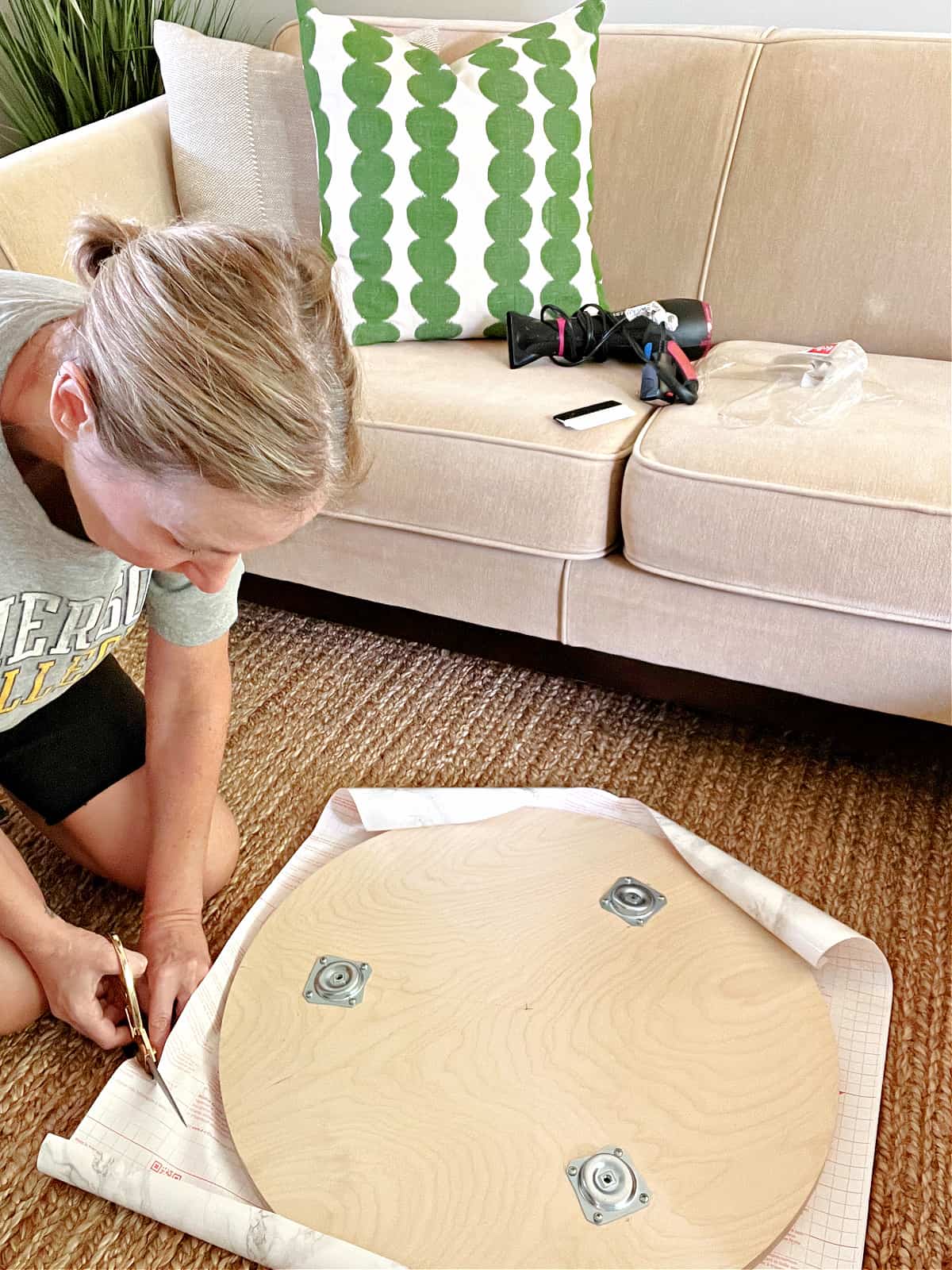 woman cutting contact paper around coffee table top