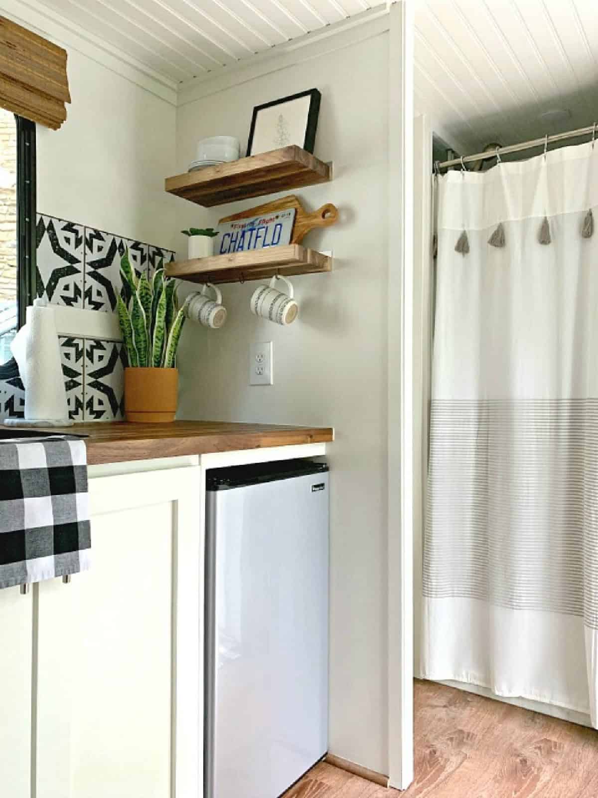 RV Camping Storage Ideas for Better Organization photo RV kitchen corner with wood shelves for storage that hold dishes and a picture