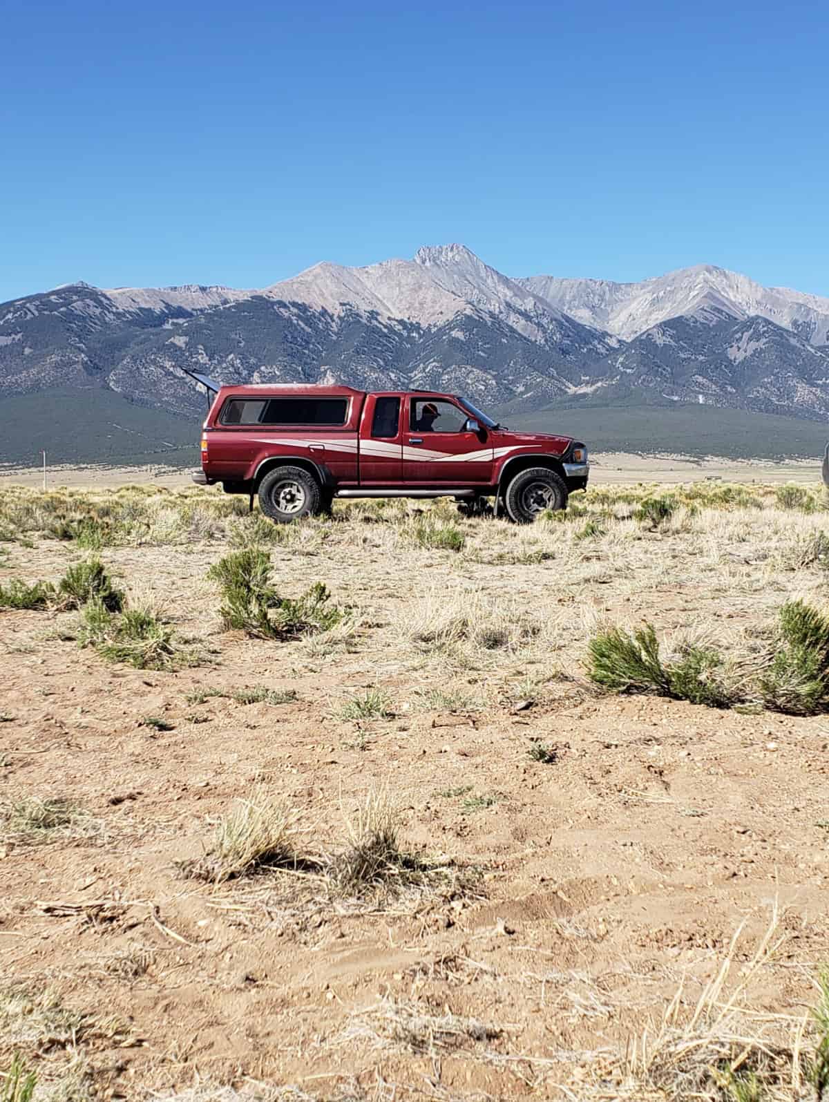 How to Find Campgrounds and Book a Good Campsite shot truck in front of the mountains at a Hipcamp campsite