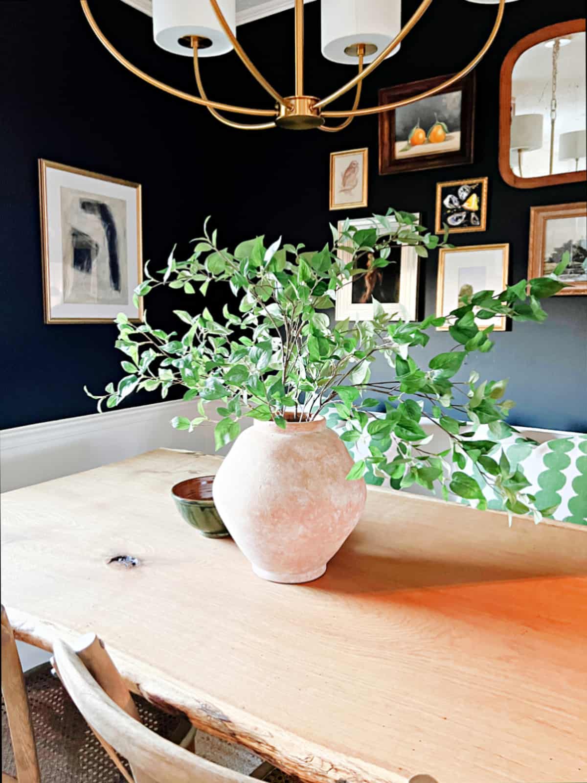terracotta vase on table in small breakfast nook wth black painted walls