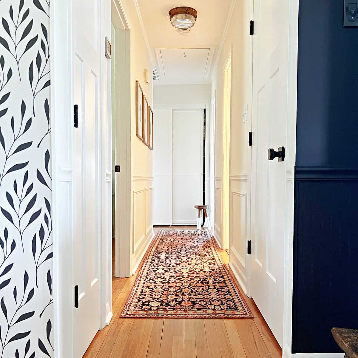 narrow hallway painted white with rug runner