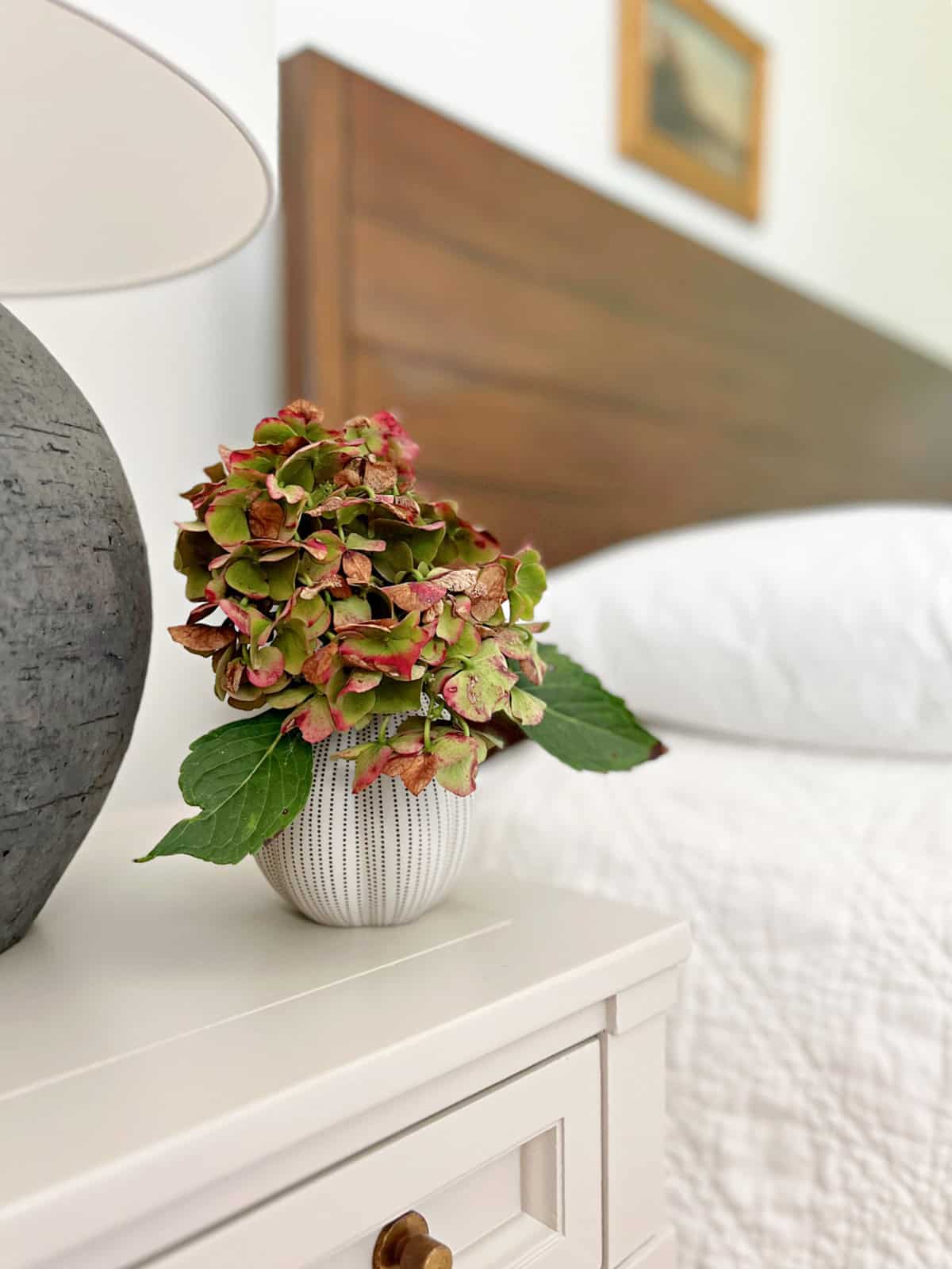vase of flowers on nighstand by bed