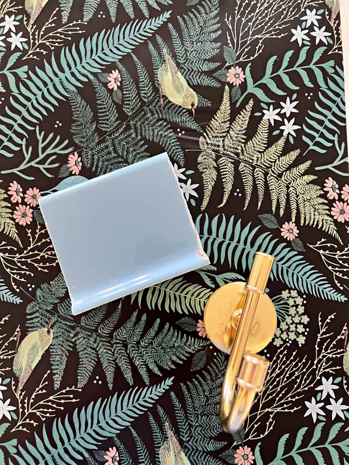 wallpaper sample with light blue tile and gold towel hook